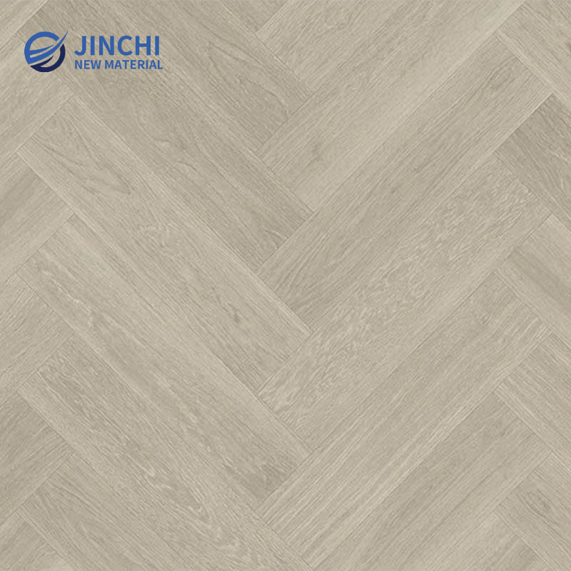 Серый виниловый ламинат с имитацией дуба, уложенный «елочкой», приклеиваемый к основанию.