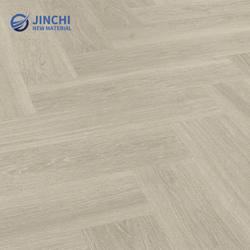 Серый виниловый ламинат с имитацией дуба, уложенный «елочкой», приклеиваемый к основанию.